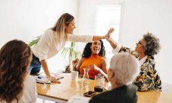 Business colleagues high fiving each other during a meeting in a boardroom. Successful businesswomen celebrating their achievement. Diverse businesswomen working together in an all-female startup.